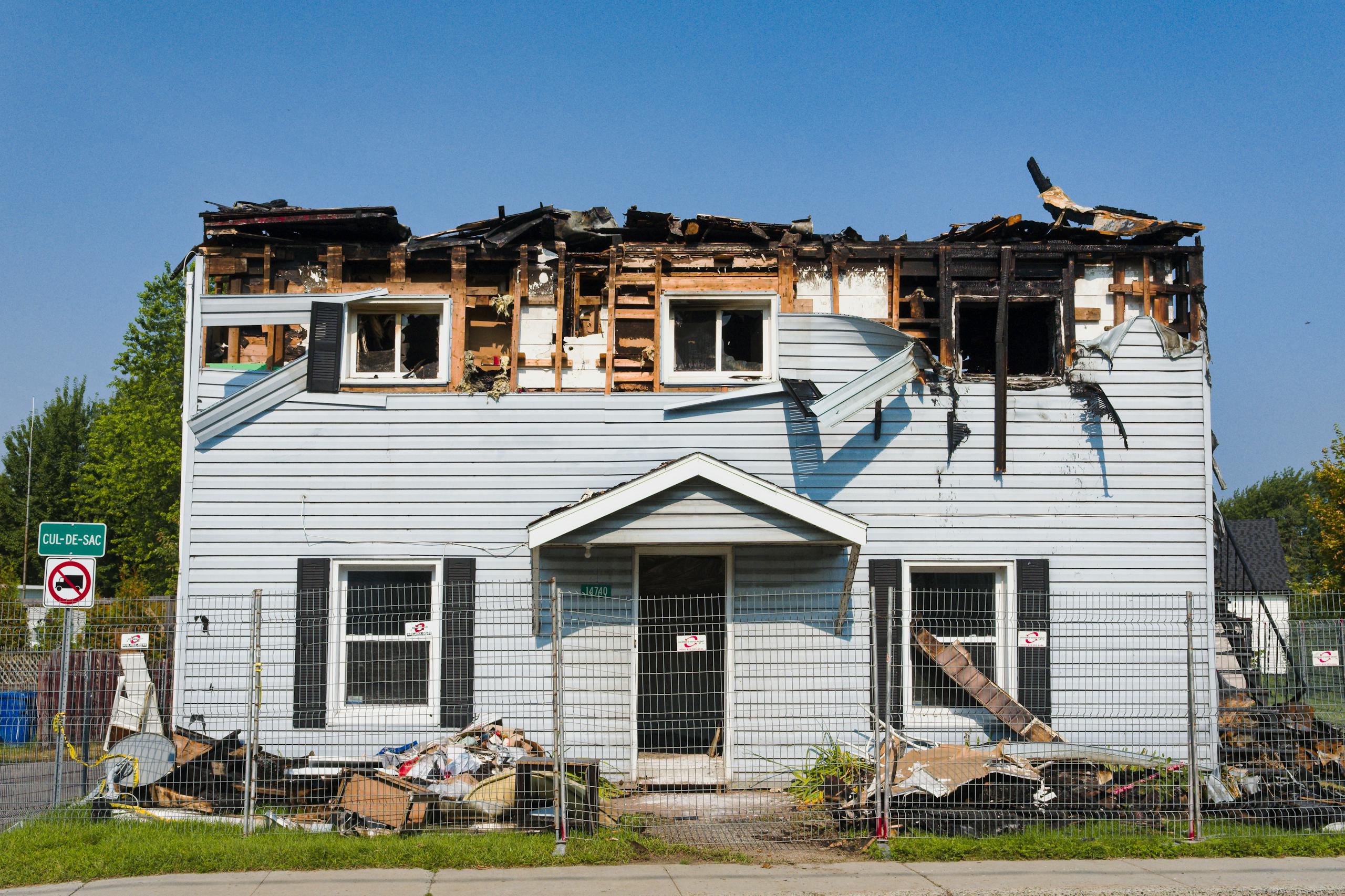 Professional Fire &Amp; Water Damage Restoration In Massachusetts 3 A damaged house with a burnt roof in bécancour, quebec, surrounded by a fence.