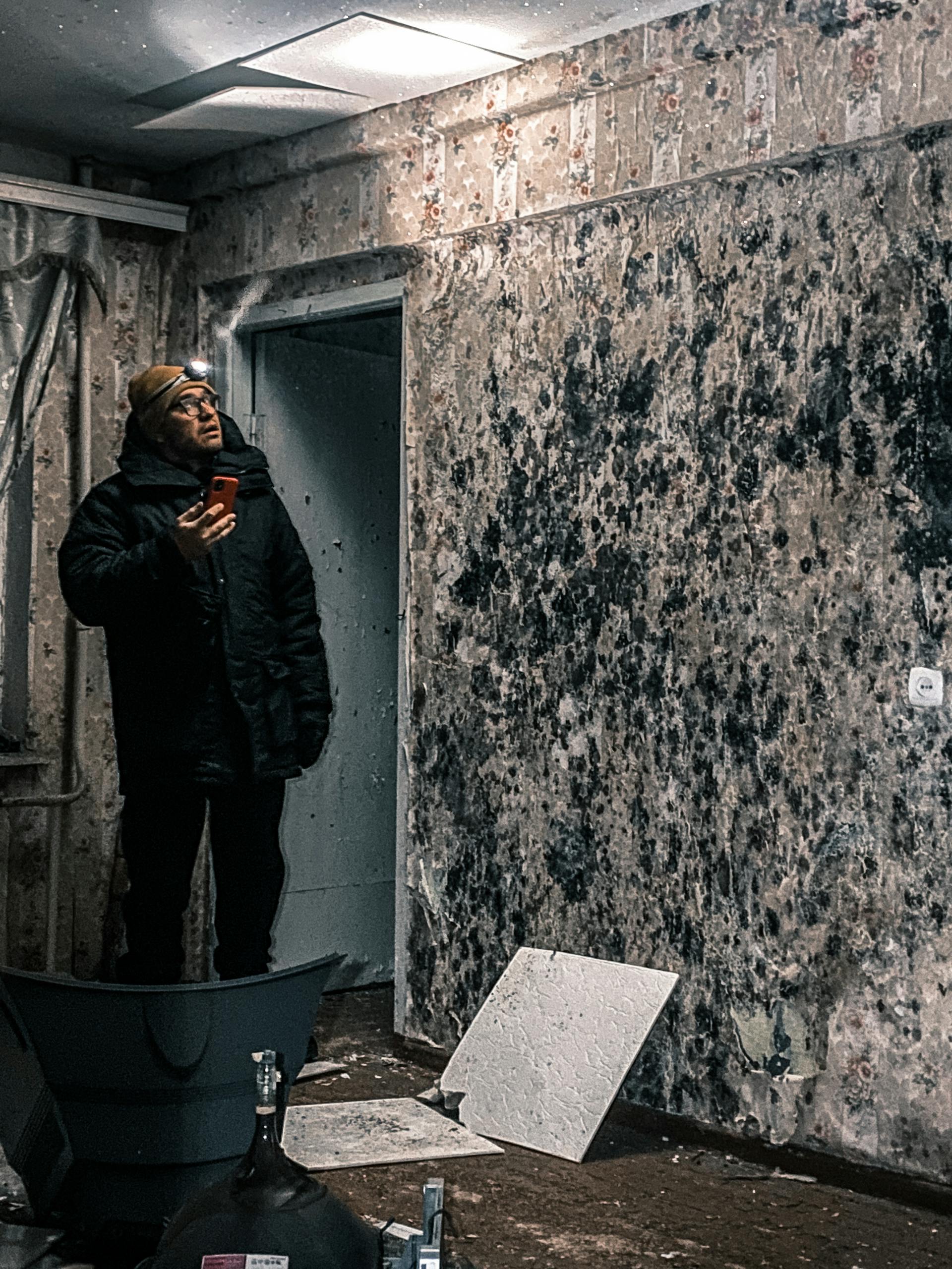 Professional Fire &Amp; Water Damage Restoration In Massachusetts 6 Man with flashlight inspects mold-covered walls in an abandoned building in vorkuta, russia.